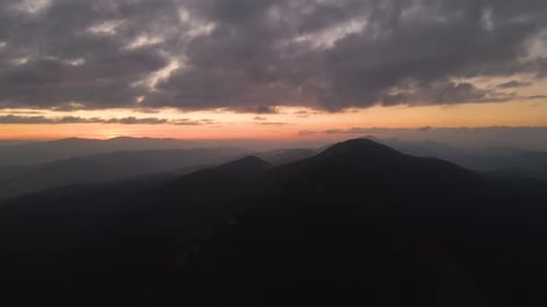 Aerial View of Foggy Evening Over High Peak with Dark Pine Forest Trees at Bright Sunset