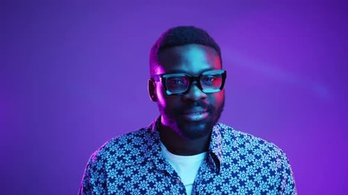 A Stylish Man Posing in Artistic Lighting While Wearing Vintage Glasses Exudes Charm and Elegance
