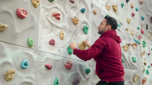 Man Climbing Rock Wall at an Indoor Gym