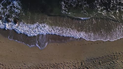 Aerial view of beach waves, slowly moving to the right
