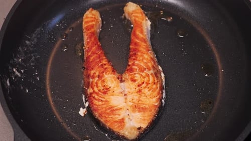 Salmon fillets fried in a hot pan, close-up footage. Healthy nutrition.
