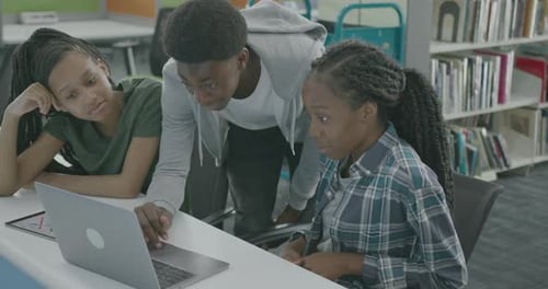 University Students using Laptop in Library Learning, helping Each other