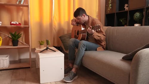 Man Playing Guitar and Recording with Smartphone