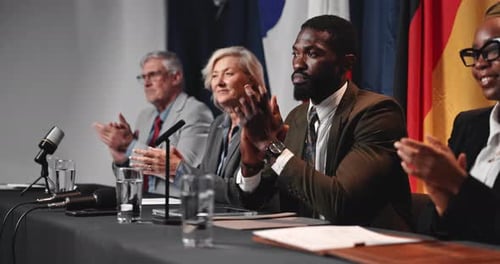 Four Adults Clapping at a Press Conference