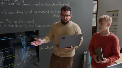 Enthusiastic Male Coding Teacher Demonstrating Script to Students on Screen
