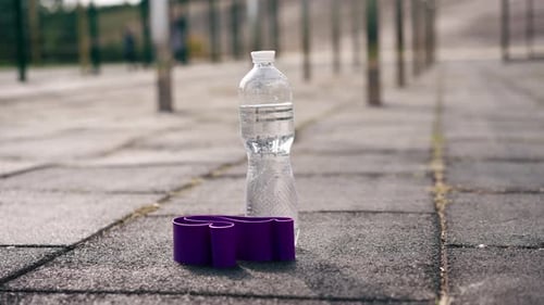 Close-up of a sports elastic band and a bottle of water that fits the legs of an athlete on outdoor