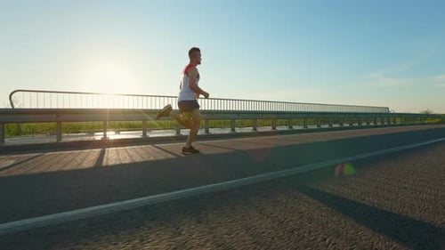 Strong Runner Jogging Quickly Across Bridge in Countryside