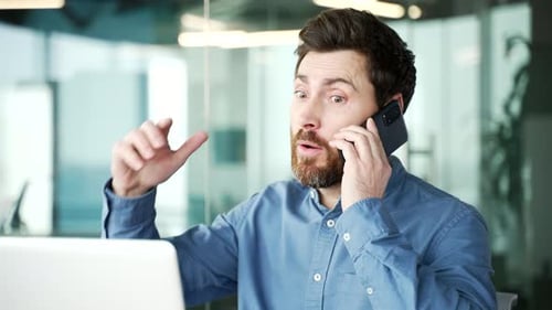Angry dissatisfied manager arguing talking on phone while sitting at workplace in business office.