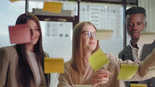 Creative Marketing Specialists are Brainstorming in Office Sticking Postit Notes on Glass Wall