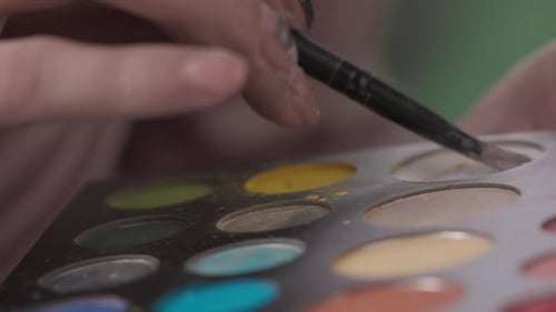 Maquiador irreconhecível usando paleta colorida de sombras