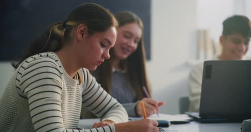 Teens Studying Together in Classroom with Laptops