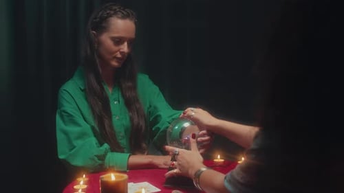 Voyant posant les mains d'une femme sur une boule de cristal