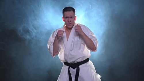 Serious Man Practicing Karate Punches in Dark Studio