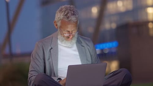 Professional Older Senior Business Man Using Laptop in Night City Park