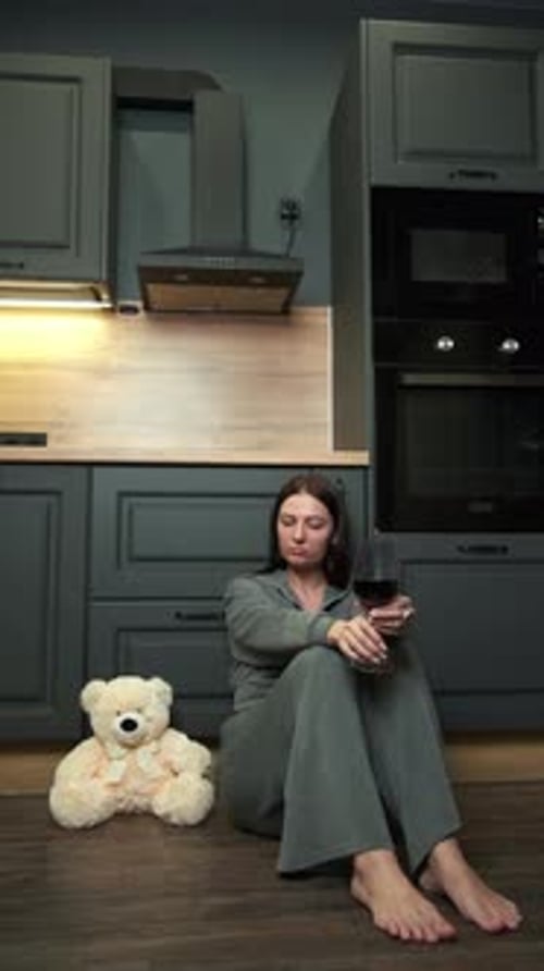 Woman Sitting on Kitchen Floor Holding Wine Glass