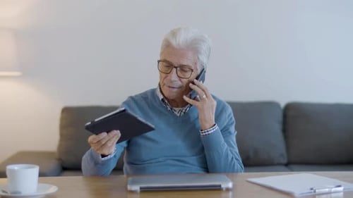 Senior Man Using Tablet While on Phone Call
