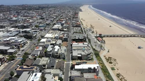 Voando acima de edifícios à beira-mar e cais em Hermosa Beach, na Califórnia, Estados Unidos, em um ambiente ensolarado