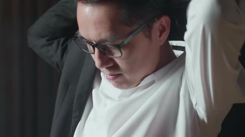 Close Up Of Asian Man With Glasses Putting On Jacket. Dressing For Celebration Event