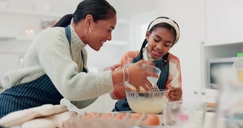 Smiling Woman and Girl Stirring Batter in Kitchen