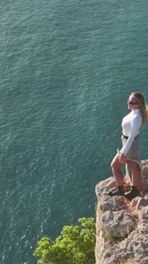 Vertical Video Graceful Model Standing on a Cliff Overlooking the Sparkling Mediterranean Sea