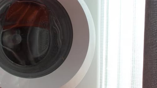 Front view of a hand opening the door of the washing Laundry. Housekeeping. Close up.