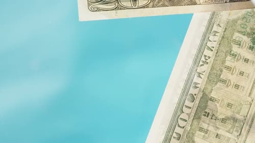 I throw twenty-dollar bills onto a glass table. On a blue background. Low angle view focus on window