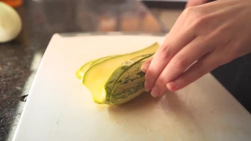Female hands cutting a green zucchini in the kitchen