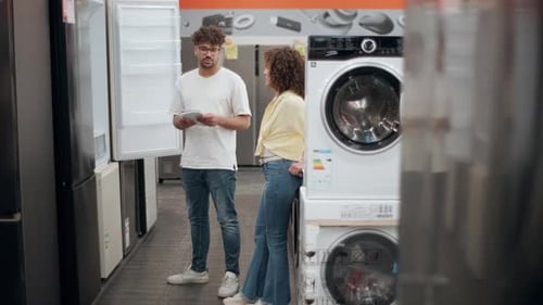Couple choosing washing machine in electronics store slow motion