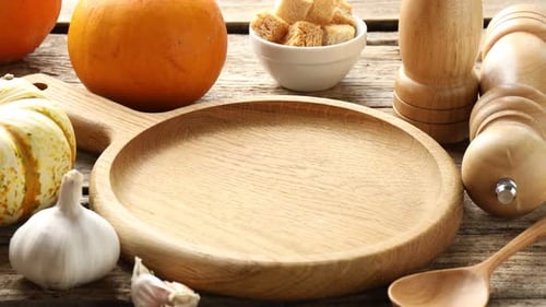 Woman serving tasty pumpkin cream soup at wooden table, closeup