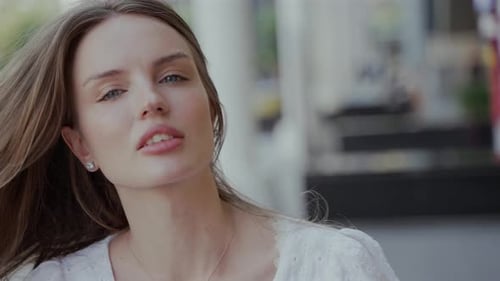 A Video Featuring a Beautiful Young Woman in a White Dress Smiling Touching Her Hair