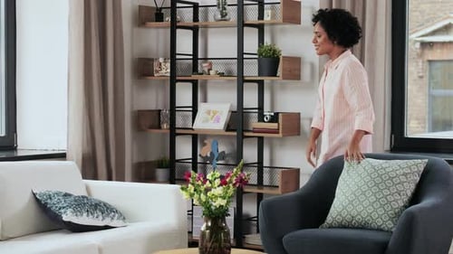 Household, Home Improvement And Cleaning Concept - Woman Arranging Cushions On Armchair And Sofa