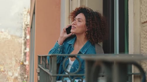 Woman Talking on Phone on City Balcony