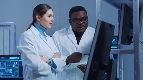 Vielfältiges Team von Mikroelektronikingenieuren diskutiert aktuelle Entwicklungen an einem wissenschaftlichen Laborarbeitsplatz von
