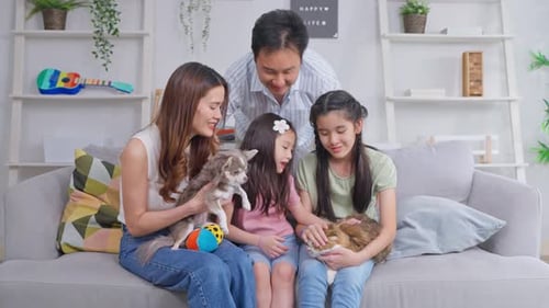 Family Relaxing on Sofa with Dog and Cat