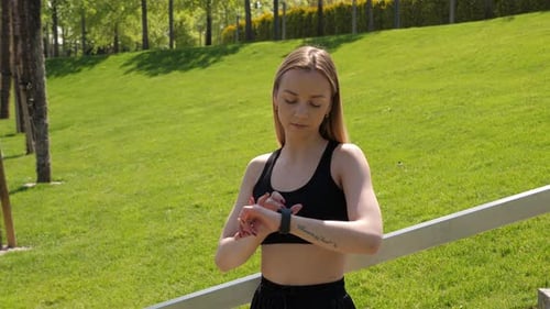 Closeup of a Woman Using a Smartwatch During a Morning Workout in the Park