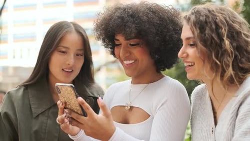 Three Friends Looking at Phone and Smiling