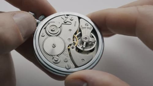 Hands Holding Vintage Pocket Watch Mechanism with Moving Gears Close Up