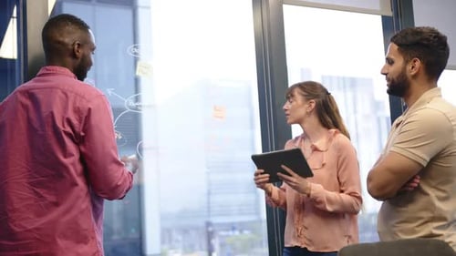 Discussing project strategy, team collaborating with tablet and whiteboard in office