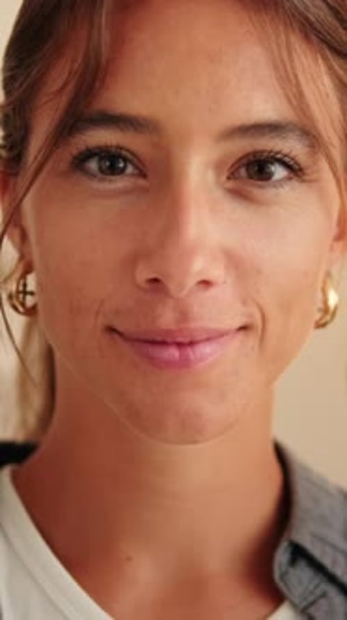 Vertical video, Close up, young smiling woman looking at camera standing in living room