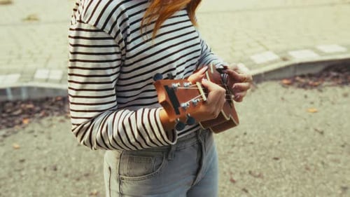 Artist Girl Plays Ukulele Musical Instrument Outside In Park