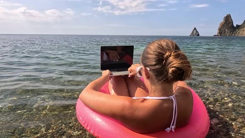 Woman Freelancer Works on Laptop Swimming in Sea on Pink Inflatable Ring Happy Tourist in Sunglasses