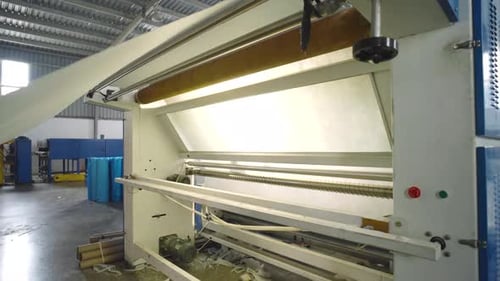 White Textile Fabric Being Fed Into Textile In Warehouse