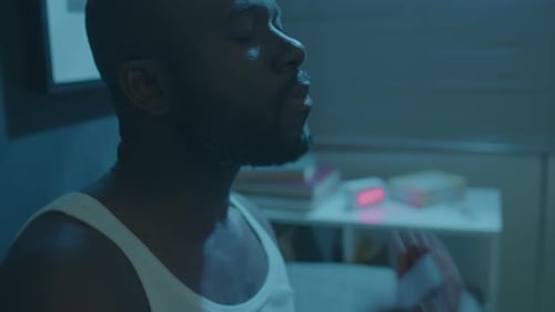 Man Drinking Water in Dimly Lit Room at Night