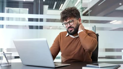 Man at Desk Working on Laptop with Neck Pain