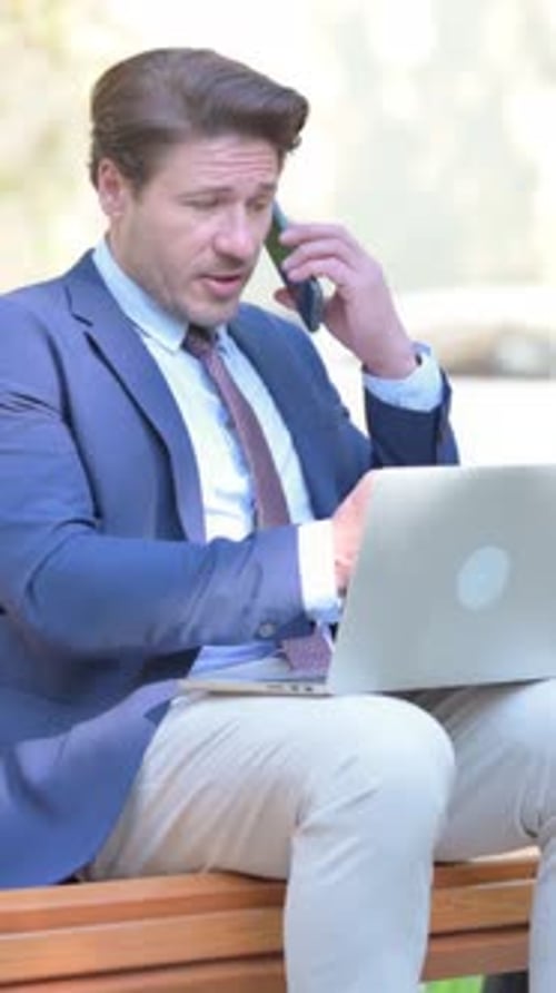 Professional Man Working on Laptop, Talking on Phone