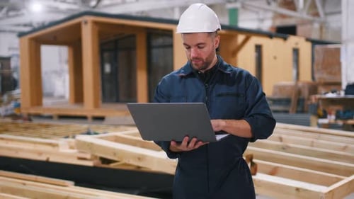 Male builder is at construction of wooden house.