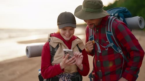 Smiling Couple Looking at Phone on Sandy Beach