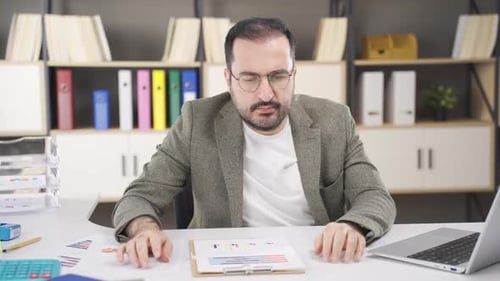 Man Reviews Business Graphs at Modern Office Desk