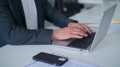Nahaufnahme männlicher Hände beim Tippen auf dem Laptop beim Chatten mit E-Mails in Gesellschaft am Tisch Unbekannter Kaukasier