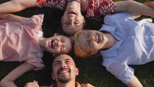 A Big Happy Family Lies on a Green Lawn in a Circle and Laughs Top View